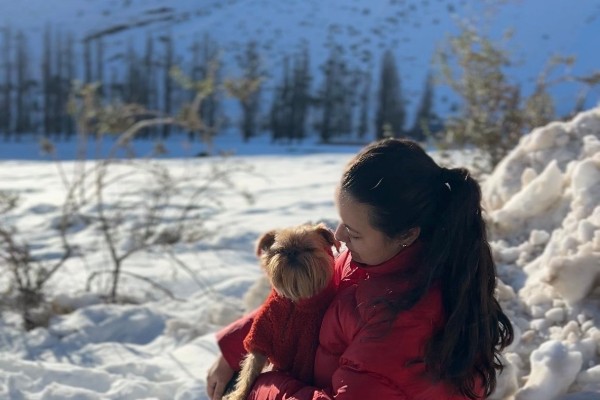Perro con chaqueta Ralfas en la nieve junto a su tutora